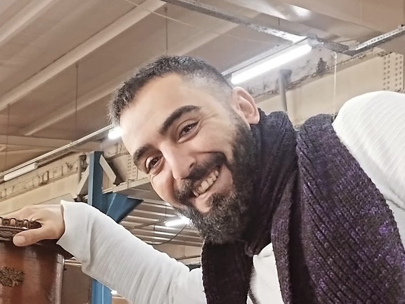 Yavuz Usta, antika pazarında elini eski bir masanın üstüne koymuş gülümsüyor